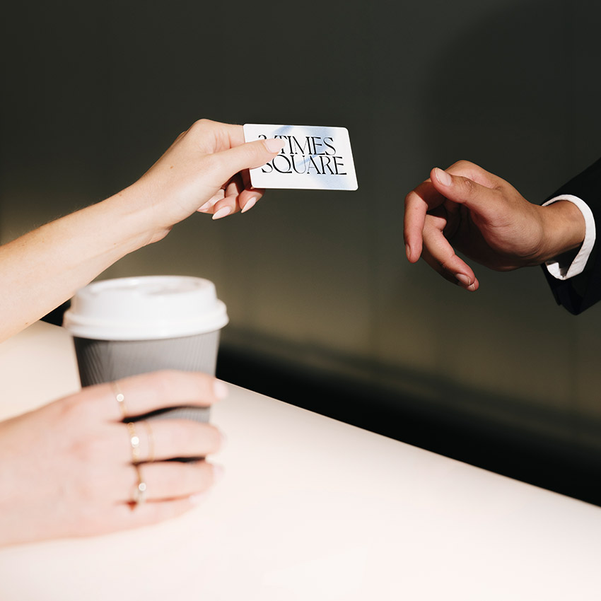 Hand with coffee and hand with business card